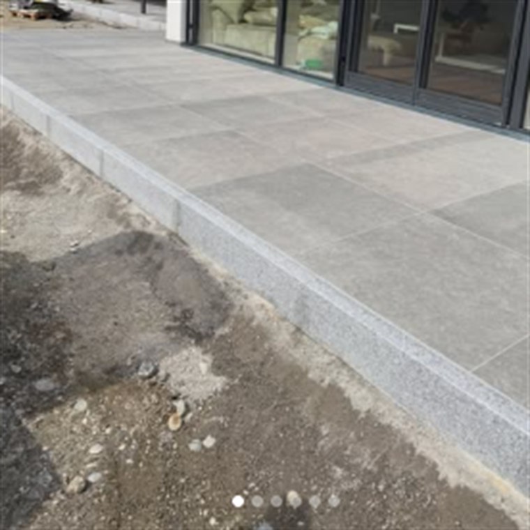 Terrasse mit großformatigen Platten in Steinoptik entlang einer Fensterfront