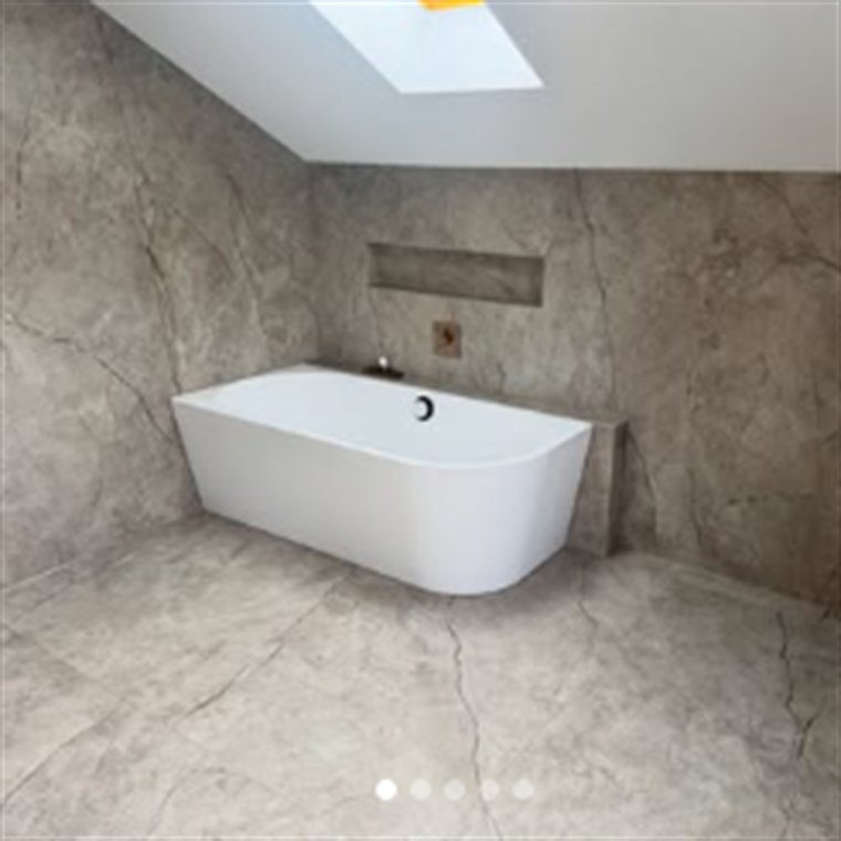 Bad unter der Dachschräge mit großformatiger Marmoroptik und freistehender Badewanne